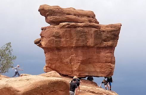 People walking by and under large red boulders