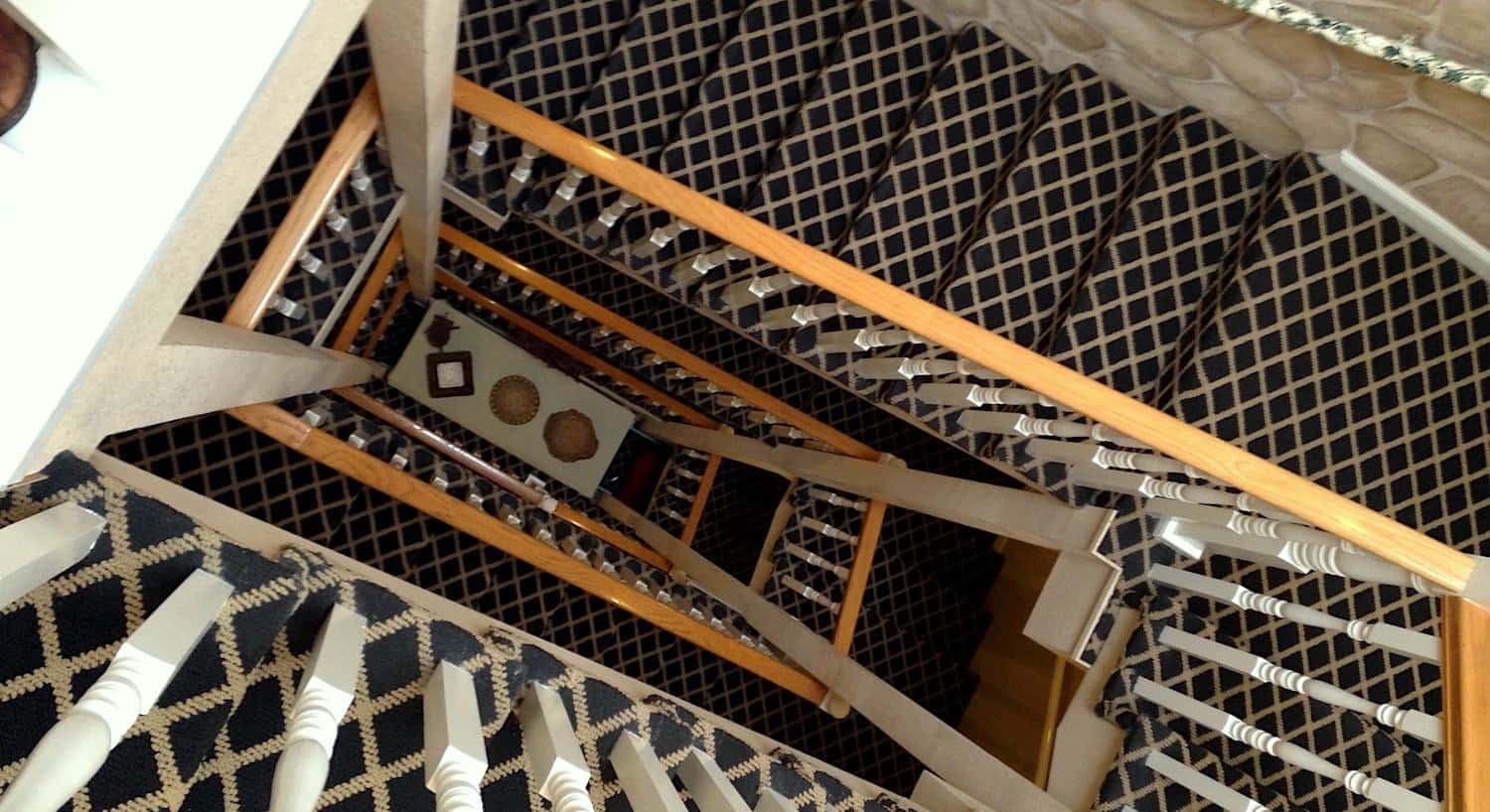 View from the top down of painted white spindel railing and carpeted staircase with multiple levels