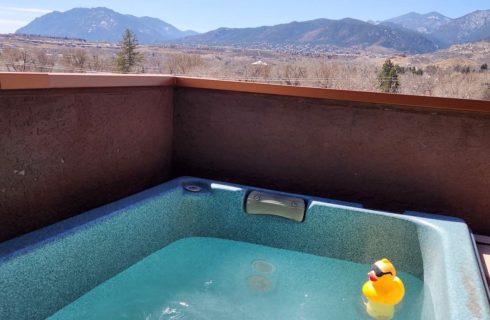 Balcony patio with hot tub, yellow duck, and view of the mountains in the background