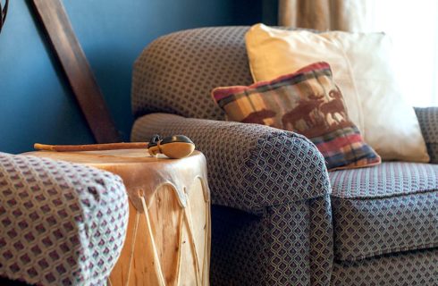 Close up view of upholstered armchair and Native American drum near a window