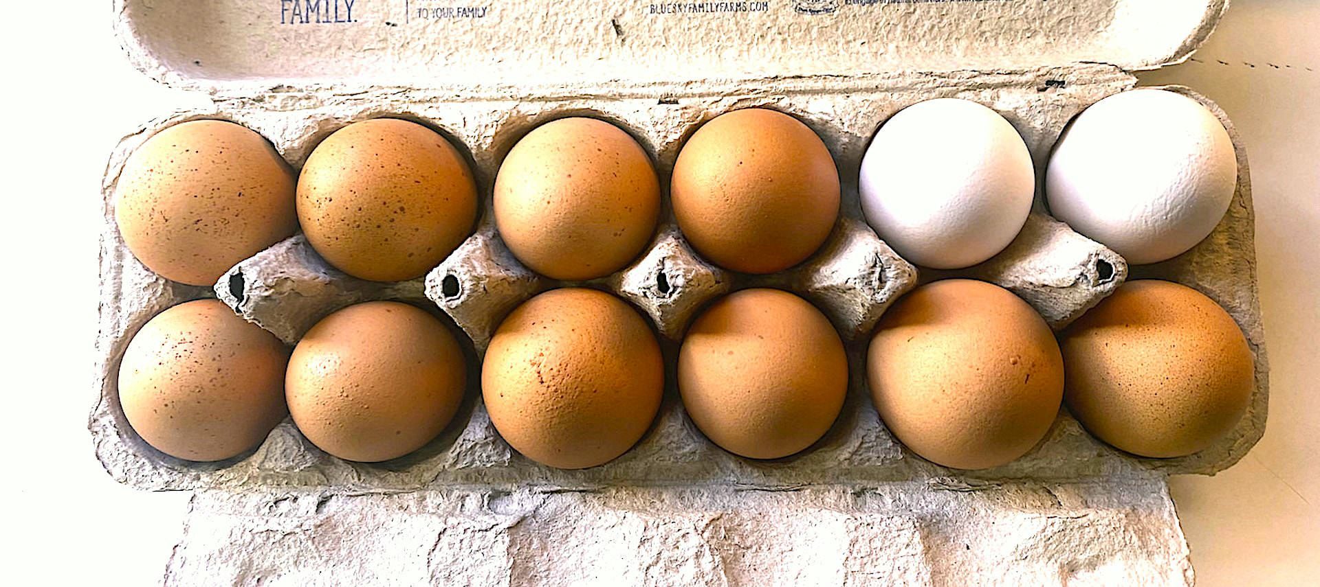 Close up view of brown and white eggs in a tan egg carton