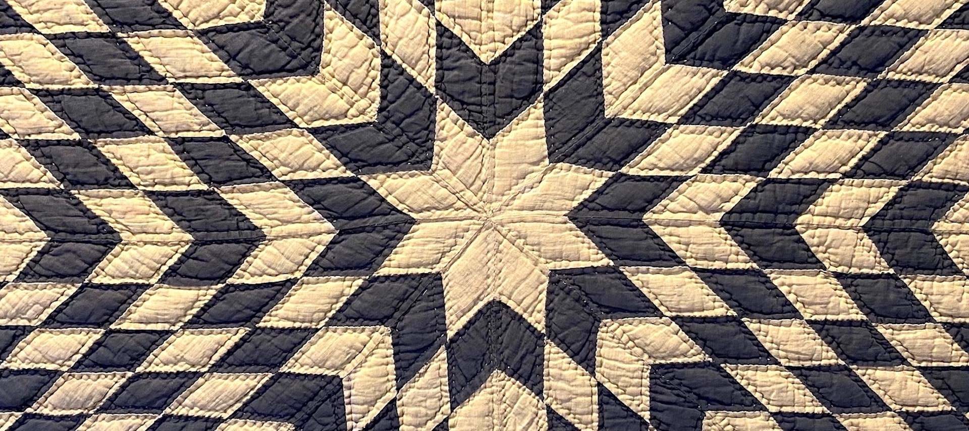 Close up view of a quilt with black and cream star design