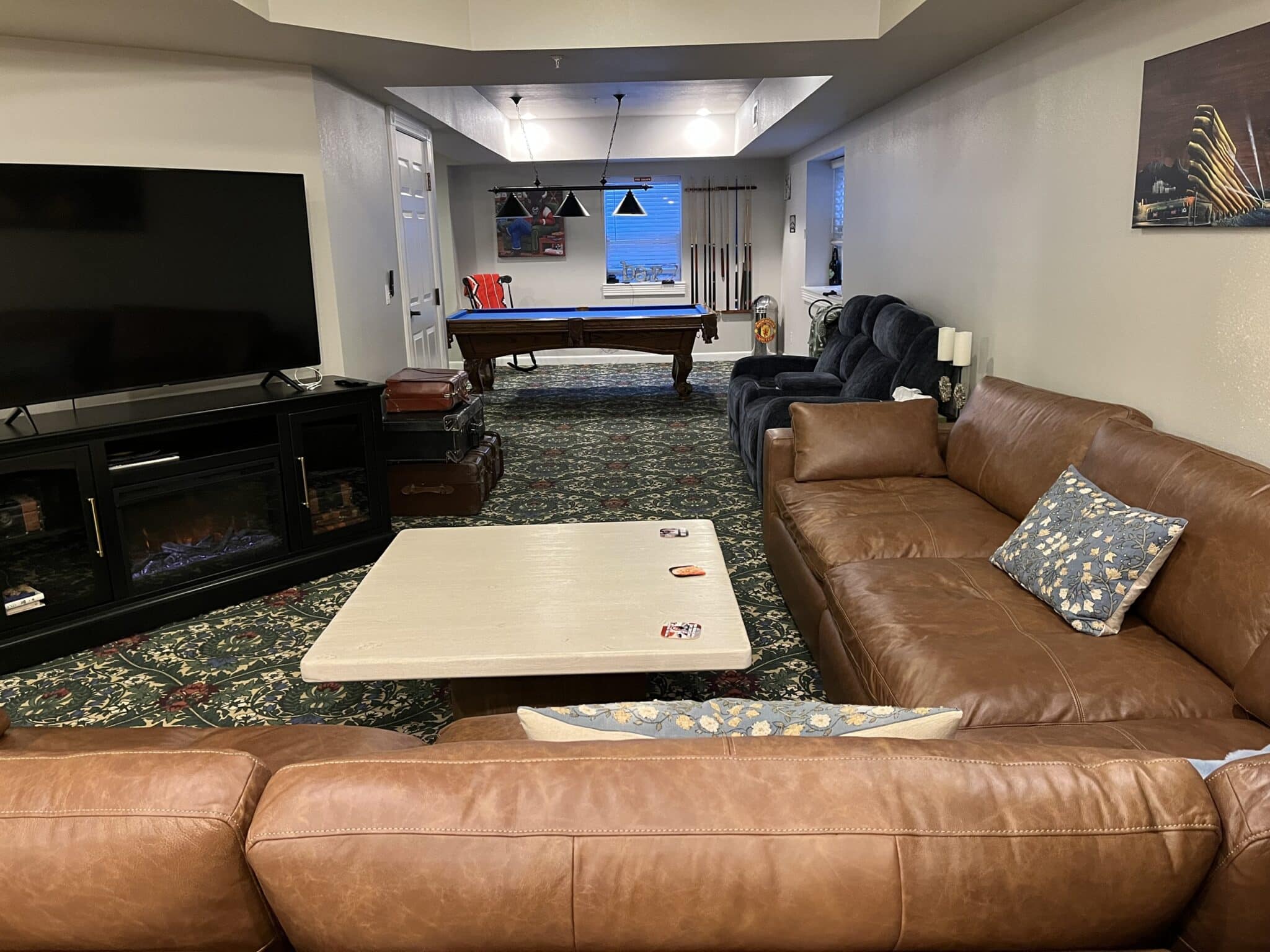 Close up view of a dining table with multicolored tablecloth, red plate with fruit cup, laptop, coffee cup, and carafes with water and orange juice